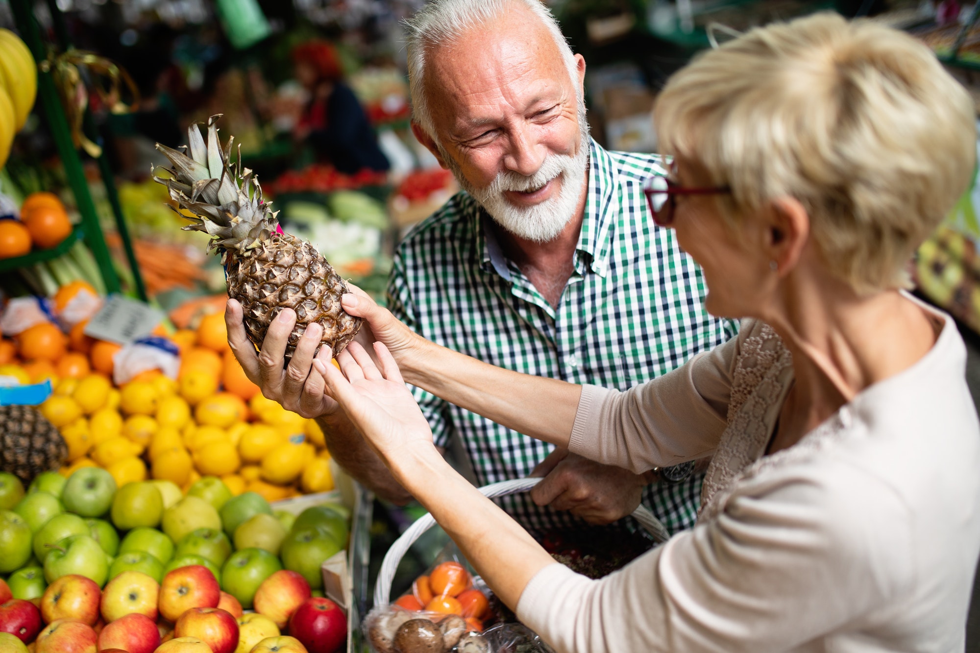 Senior couple buying fresh vegetables and fruits at the local market