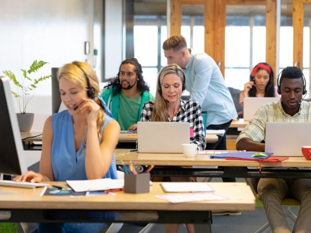 Front view of diverse customer service executives working at desk in a modern office